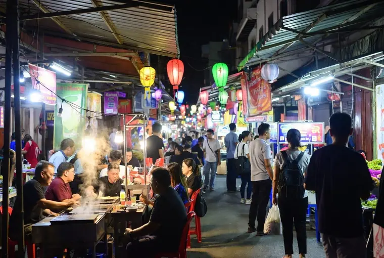 Busy night market street in Hat Yai with food stalls, lights and people