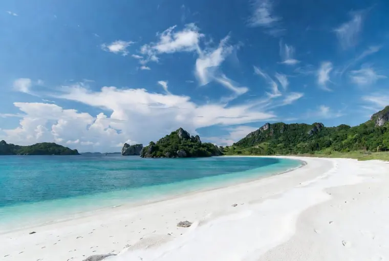 Beautiful white sand beach on Koh Phangan with turquoise water and green hills