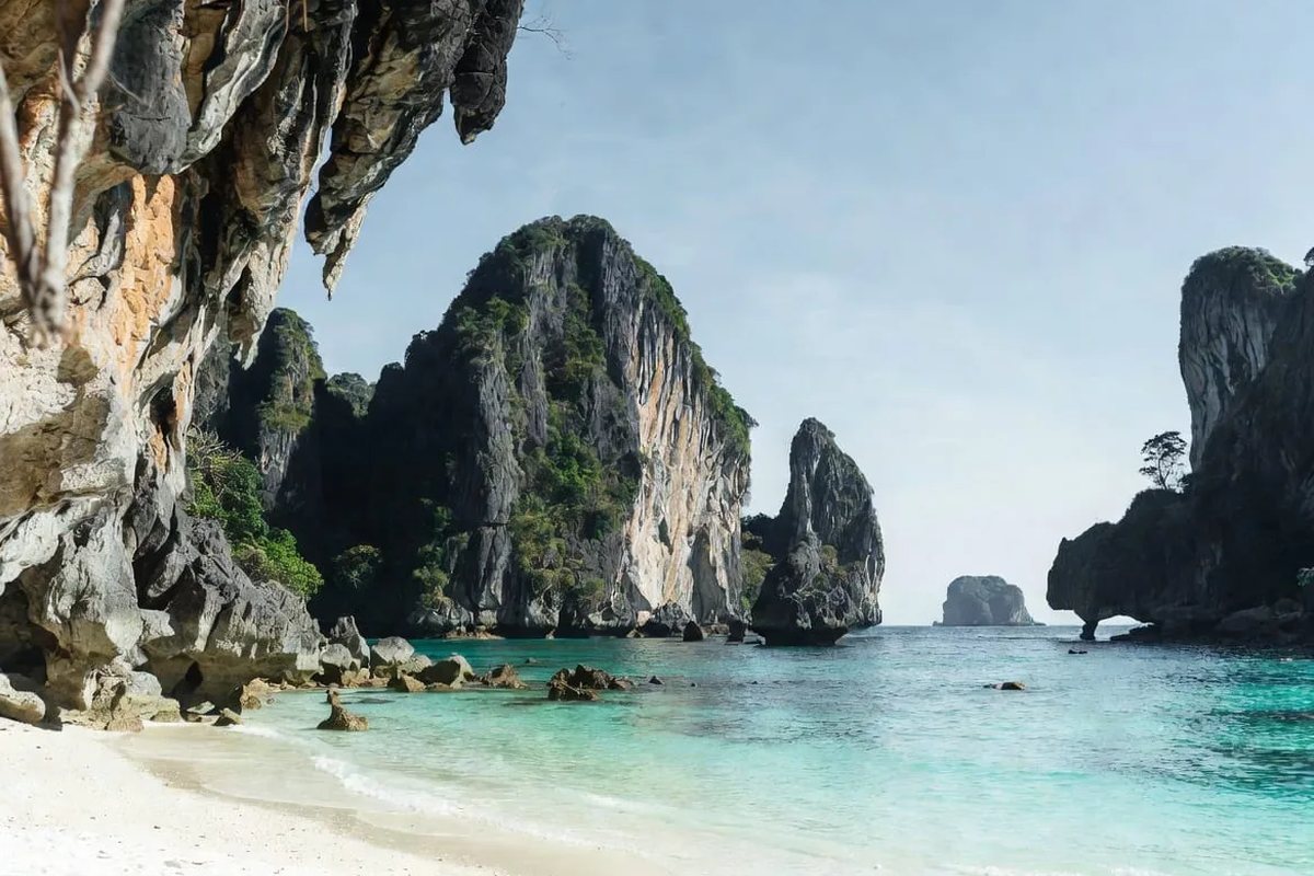 Turquoise water and limestone karst cliffs above a white sand beach on the Andaman coast near Krabi, one of the best places to visit in Thailand on a 30-day Thailand itinerary