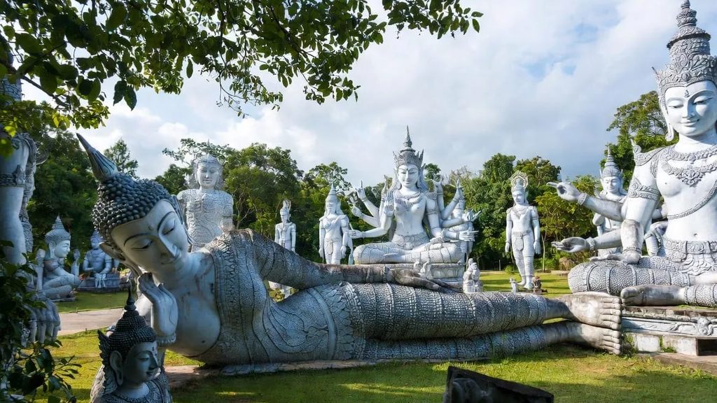 Giant concrete Buddhist and Hindu statues among trees and grass at Sala Kaew Ku sculpture park in Nong Khai, a highlight of Thai culture on the Mekong