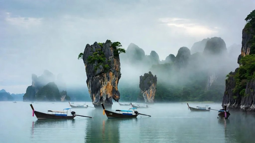 Longtail boats moored among misty limestone karst islands in Phang Nga Bay, the province that administers the Similan and Surin national parks