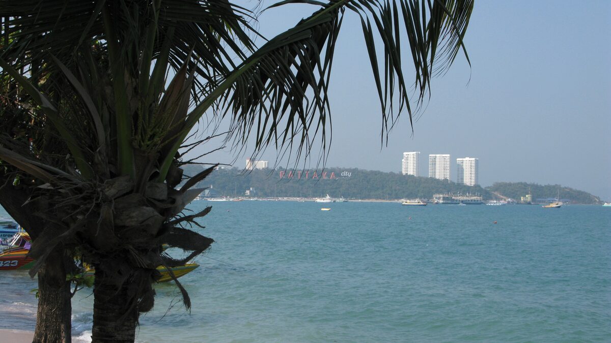 Pattaya Bay seen from the beach with the hillside PATTAYA CITY sign and high-rise hotels behind it, the base city for this Pattaya travel guide