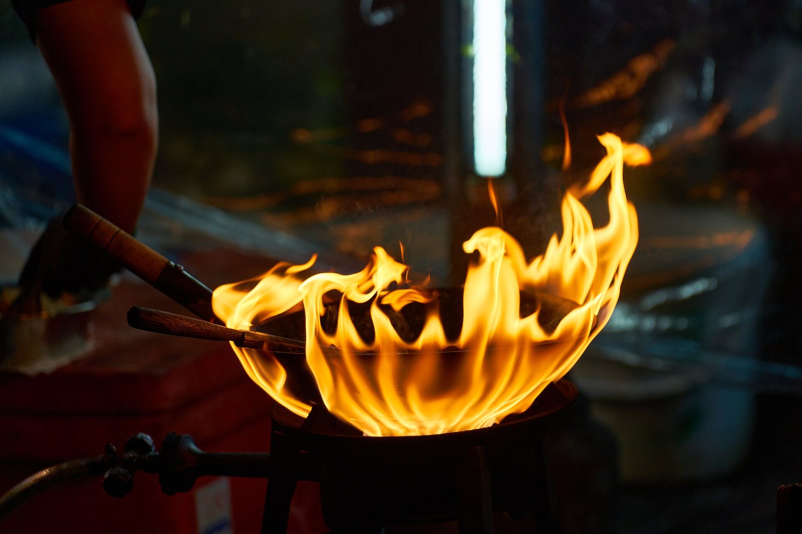 Flames leaping from a street vendor's wok at night in Bangkok's Chinatown, the signature cooking style behind Yaowarat's Bangkok street food scene