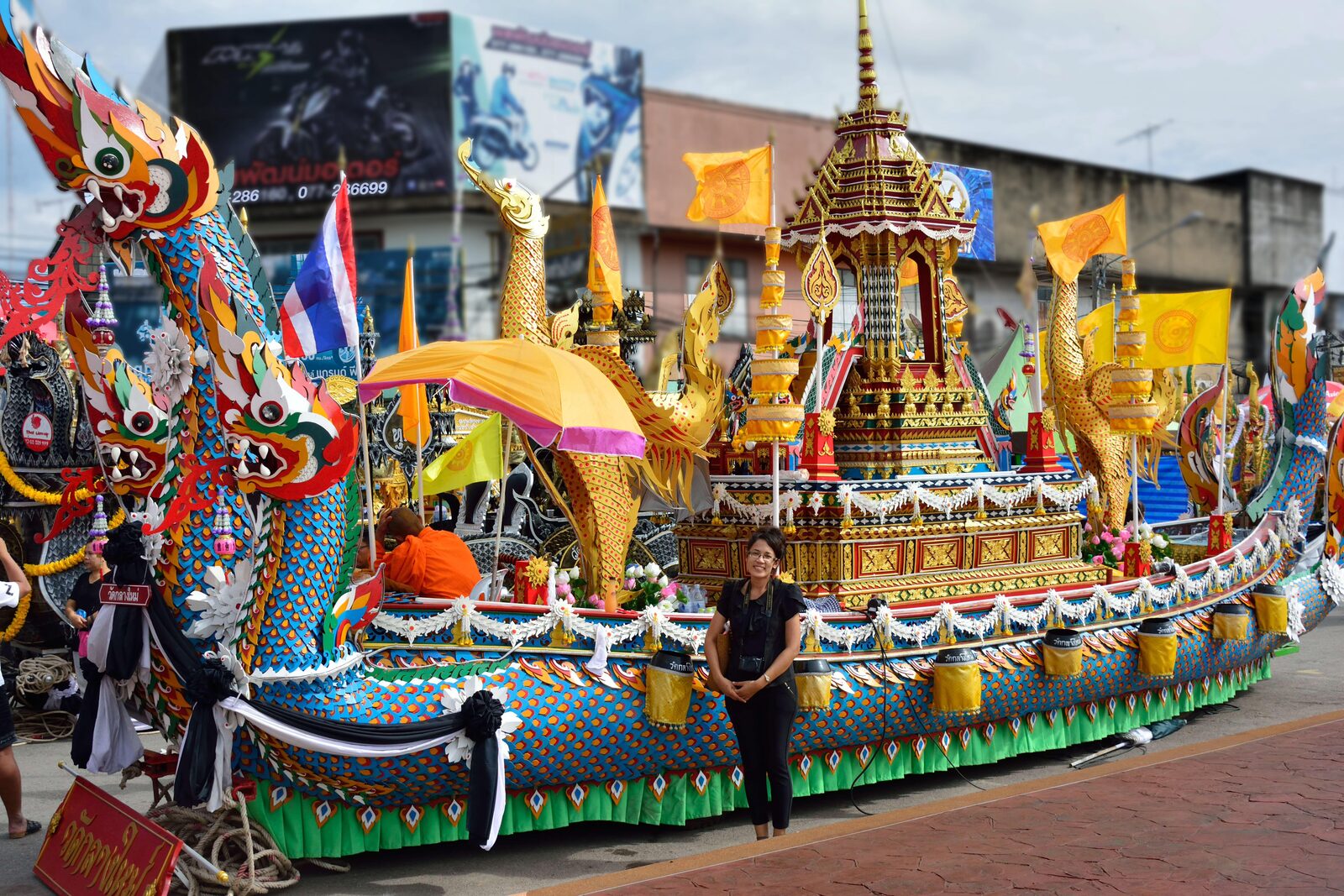 A brightly painted Chak Phra festival float with carved naga prows and a gilded Buddha shrine parked on a Surat Thani street, one of the best places to visit in Thailand in late October