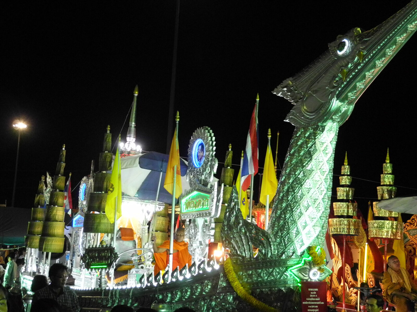A silver and green Chak Phra float with a tall carved naga prow and tiered offering trees glowing at night in Surat Thani during one of the biggest Thai festivals 2026 events