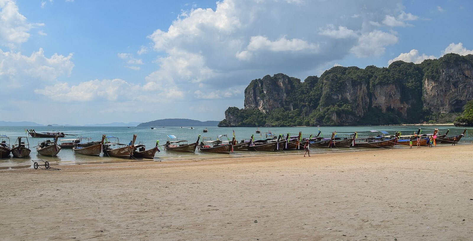 Wooden longtail boats lined up on the white sand of West Railay Beach in Krabi beneath limestone cliffs, voted the second best beach in Asia and one of the best places to visit in Thailand