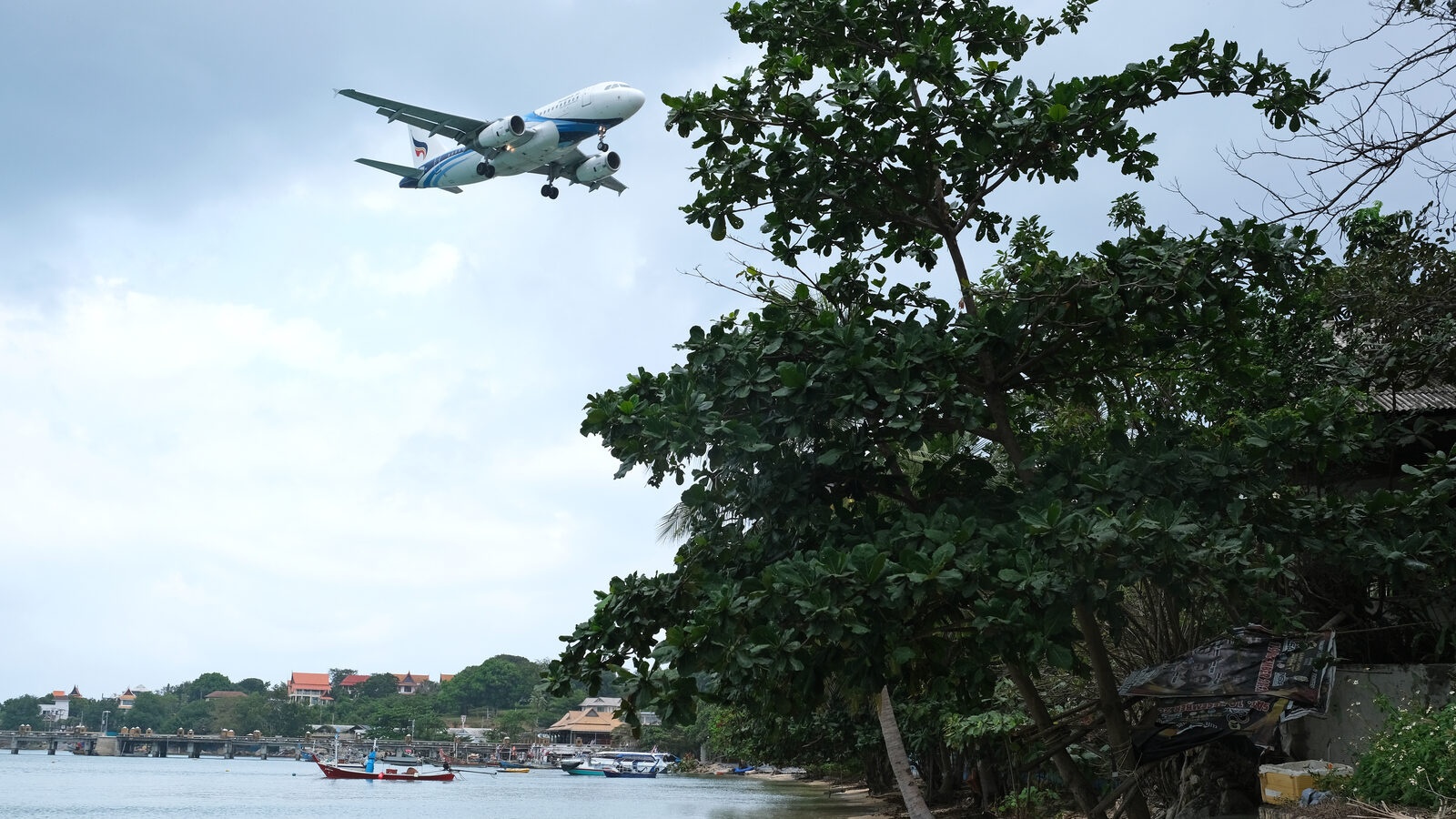 A Bangkok Airways Airbus A319 on final approach over Bangrak Beach and fishing boats as it arrives at Samui Airport, one of Thailand's busiest domestic flight routes