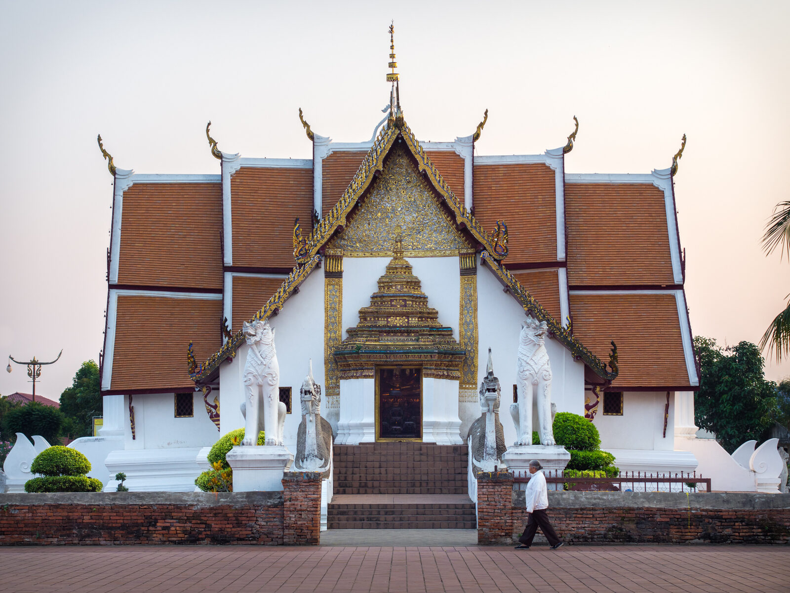 Wat Phumin temple in Nan at dusk, with its cruciform roof, gilded gable and two white naga guardians flanking the entrance stairs, a highlight of northern Thai culture