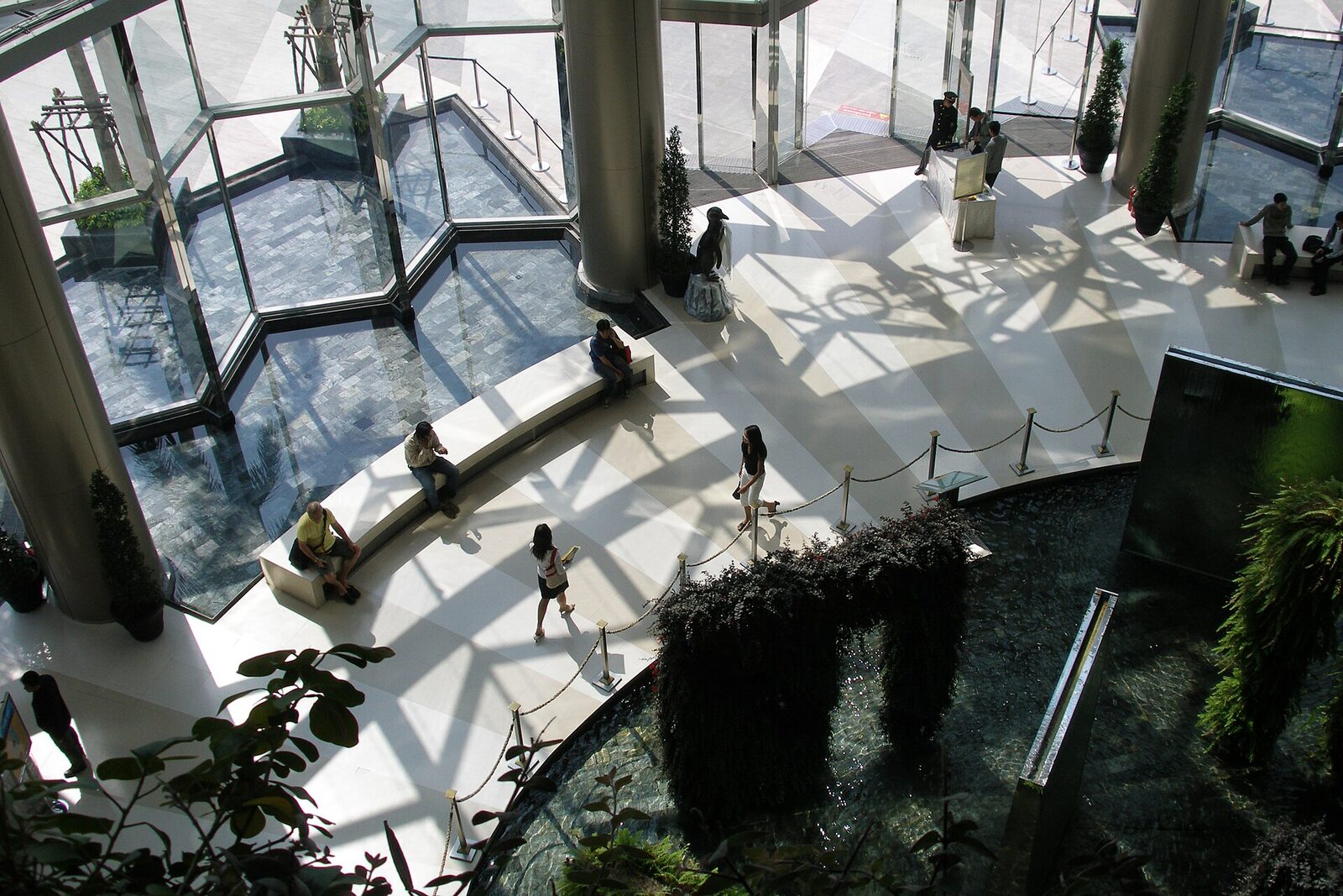 The light-filled main hall of Siam Paragon in Bangkok, with shoppers crossing the atrium above a water feature, a landmark of Bangkok tourism shopping