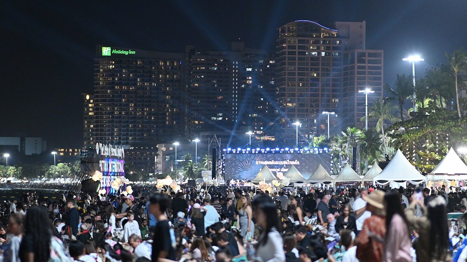 Thousands of people packed onto Pattaya Beach at night in front of the lit main stage of the Pattaya International Fireworks Festival, with Beach Road hotels glowing behind, the centrepiece of this Pattaya travel guide to November 2026