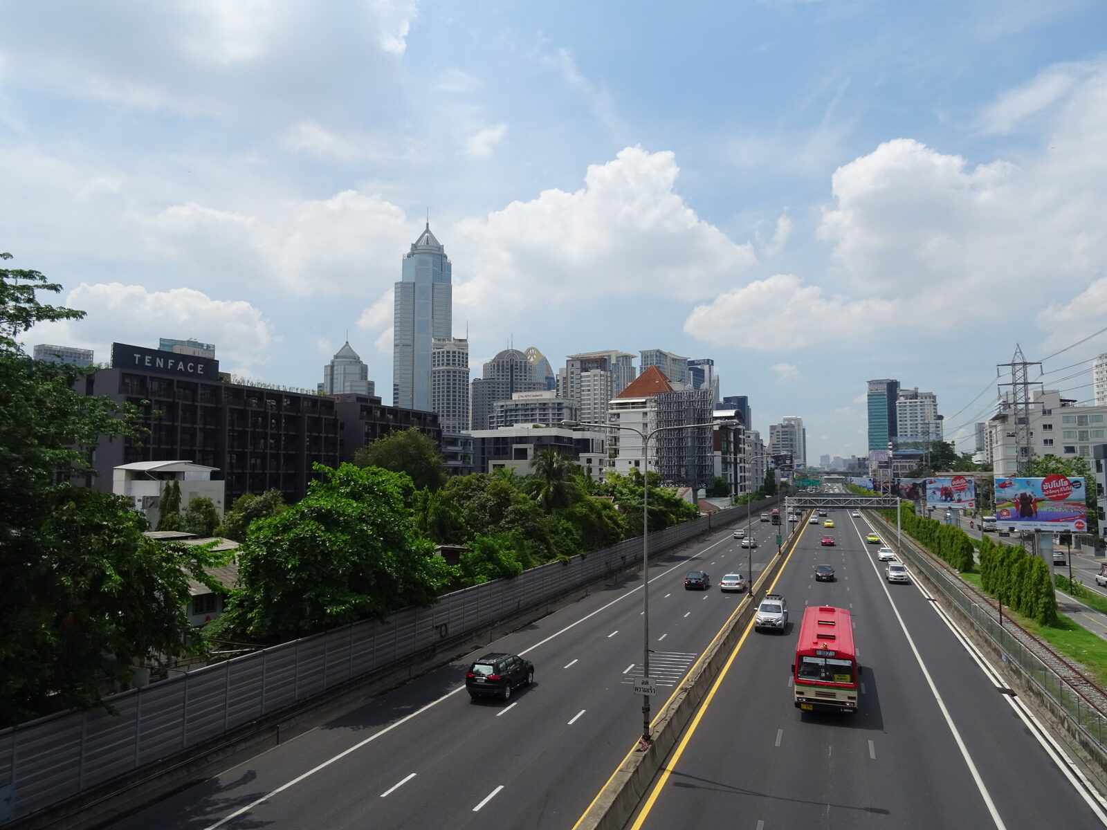 Traffic and a red public bus on the Chaloem Maha Nakhon Expressway in Bangkok with the Sukhumvit skyline behind, the route where expressway tolls are waived on Chulalongkorn Memorial Day
