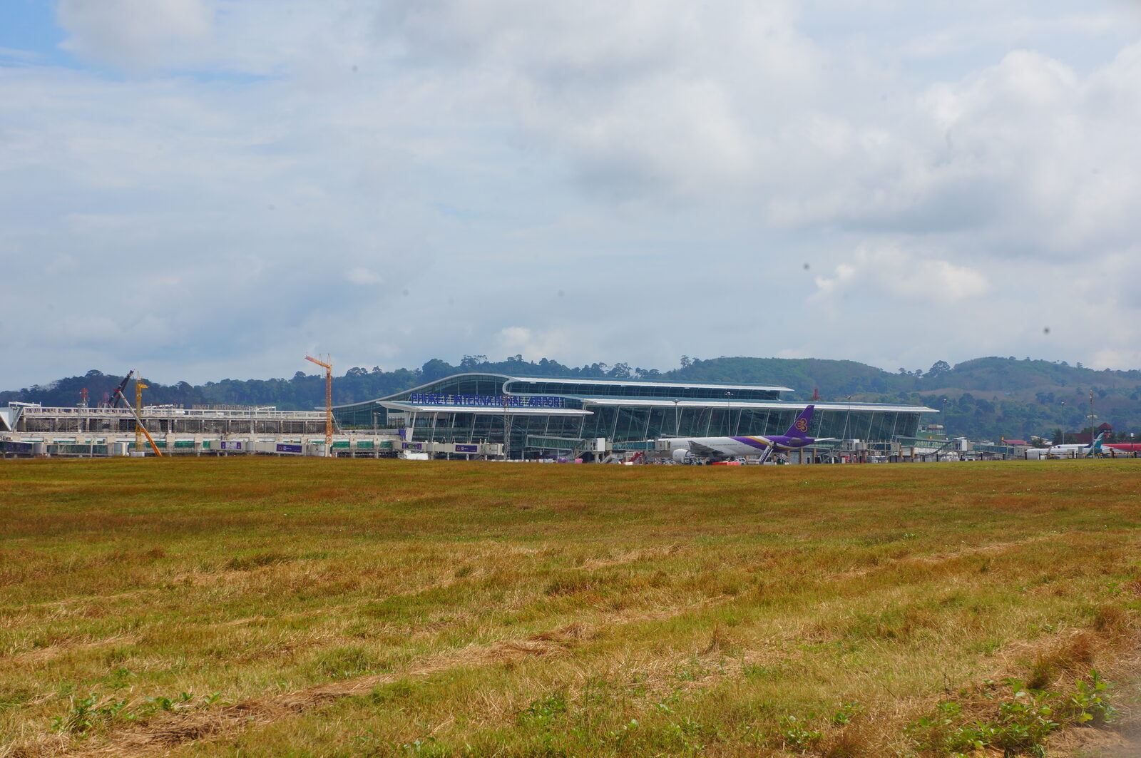 The international terminal building at Phuket International Airport with palm trees and the covered drop-off kerb in front, the arrival point for travellers who travel to Thailand on the new Heathrow route