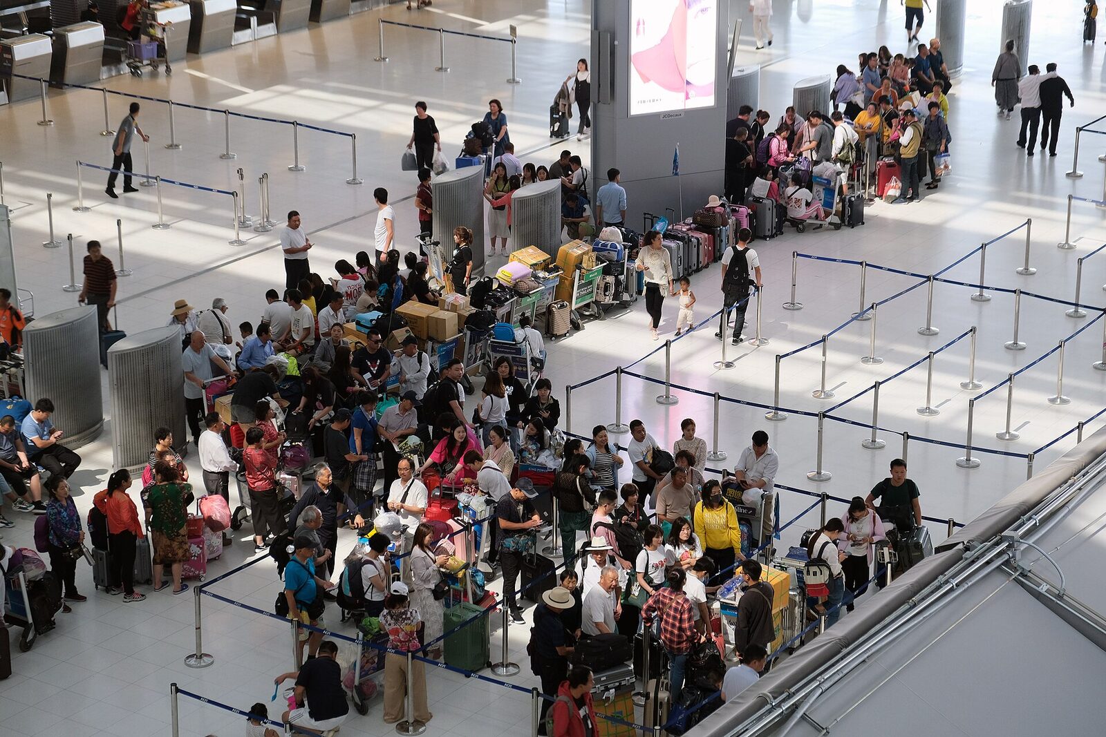 Travellers with luggage trolleys queuing in long roped lines at the international check-in hall of Suvarnabhumi Airport in Bangkok, where the proposed 1,000-baht departure tax would have been collected