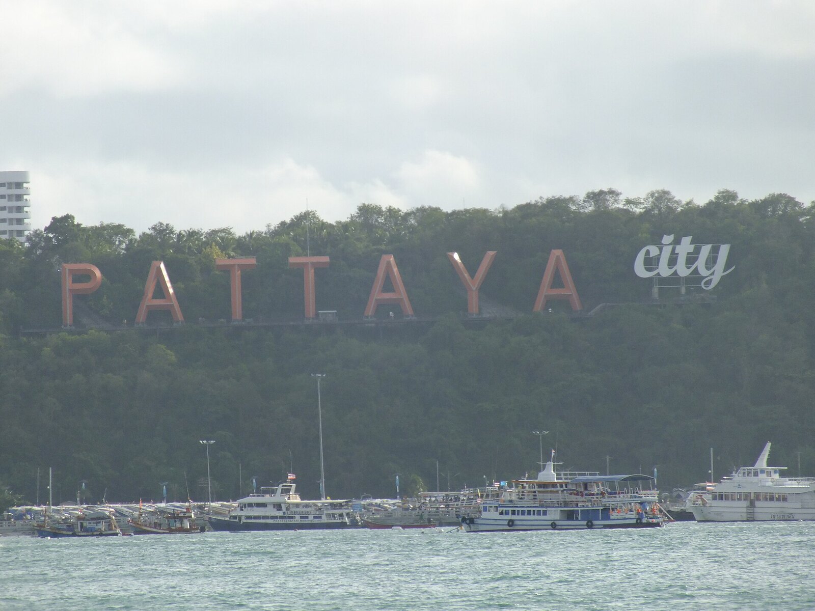 The white Pattaya City sign on the green hillside above Pattaya Beach, a landmark for visitors following a Pattaya travel guide