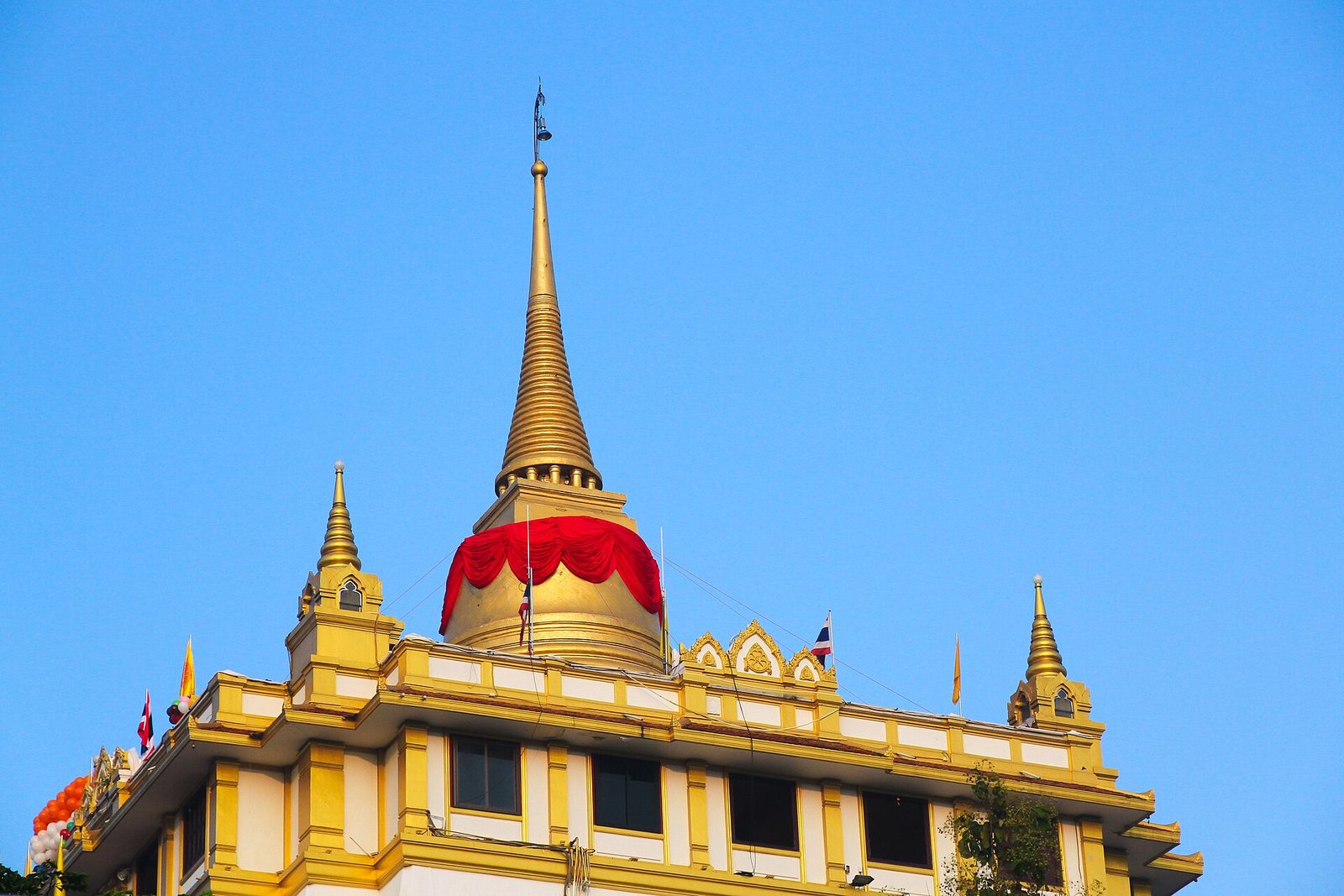 The golden chedi of Wat Saket on Bangkok's Golden Mount wrapped in red cloth against a blue sky, the symbol of the Golden Mount Temple Fair and a Bangkok tourism highlight in Thailand