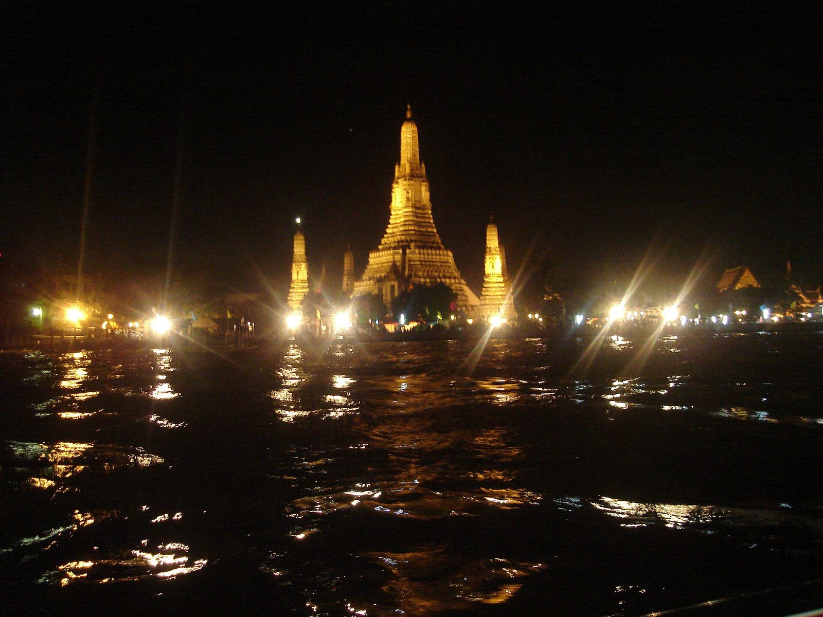 Wat Arun illuminated on the Chao Phraya River in Bangkok on Loy Krathong night, a highlight of a November Thailand itinerary