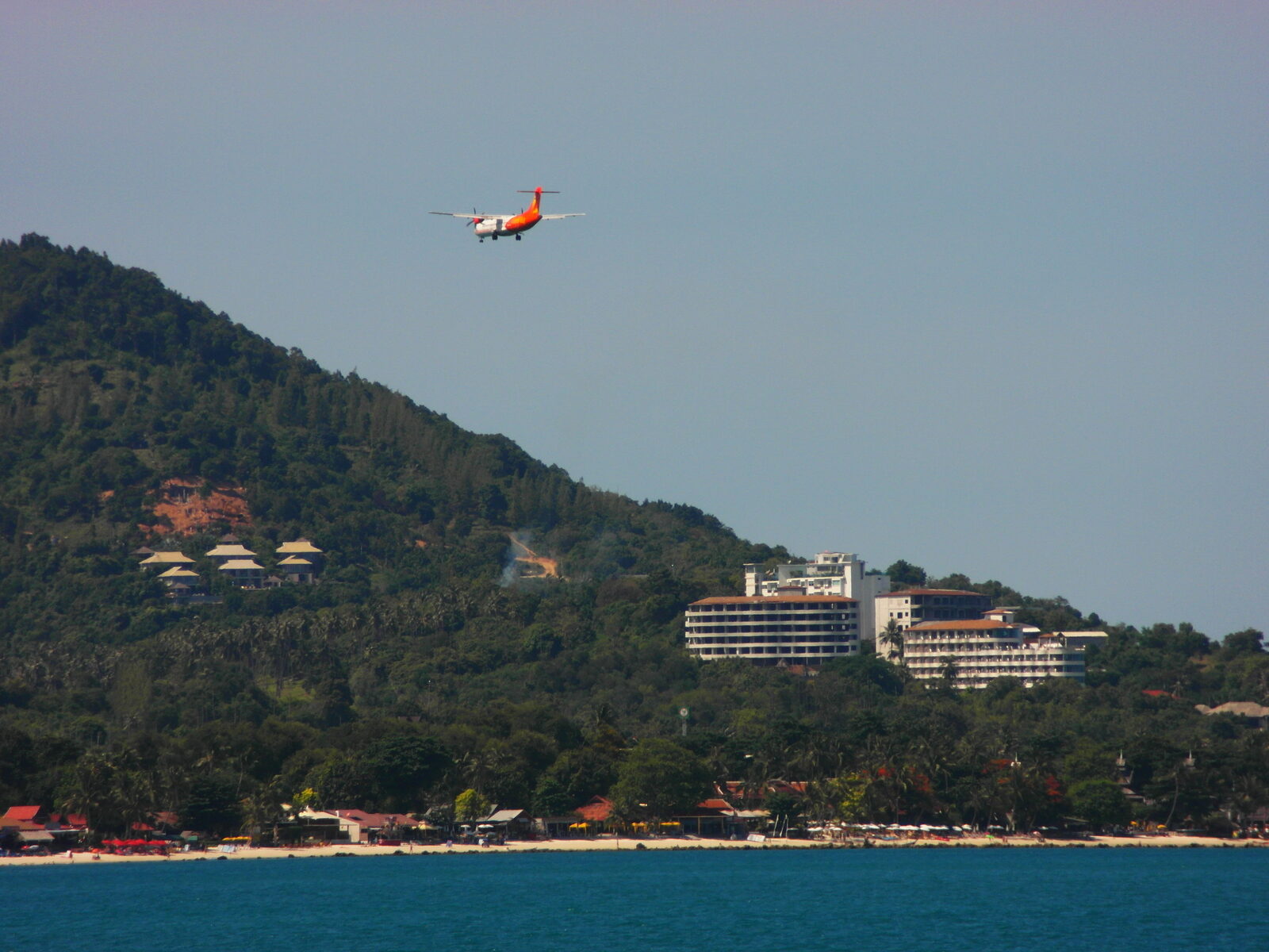 A turboprop airliner on approach to Samui airport above the hotels and palms of Chaweng Beach, Koh Samui, a key base for Thailand vacation planning on the Gulf coast