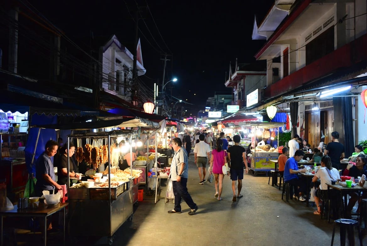 Busy night market street in Surat Thani with food stalls and people