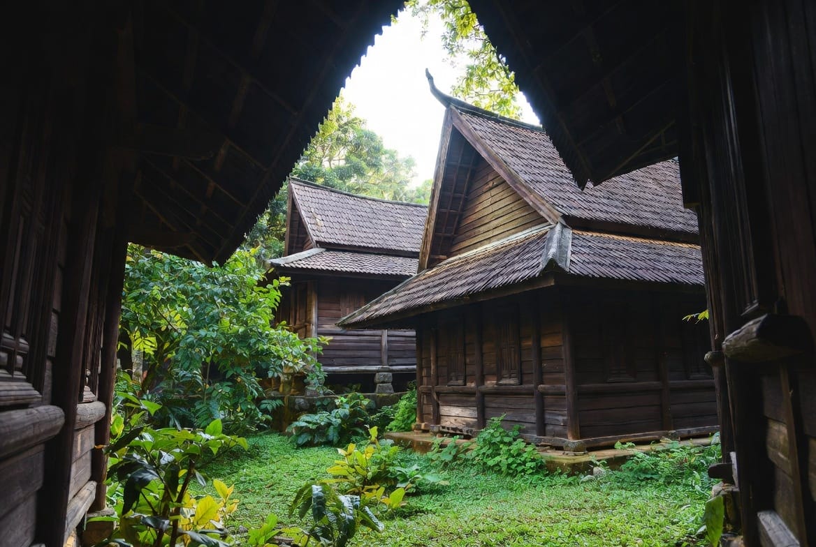 Dark wooden buildings of the Black House Museum in Chiang Rai surrounded by greenery