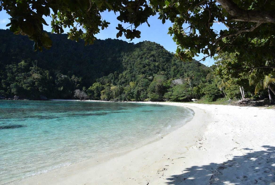 Quiet curved beach with clear water and jungle hills on a Trang Island