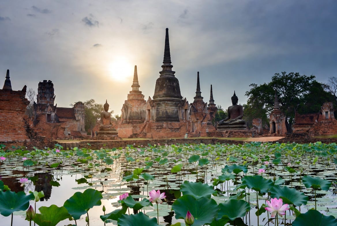 Wat Mahathat temple ruins and Buddha statues reflected in a lotus pond at Sukhothai