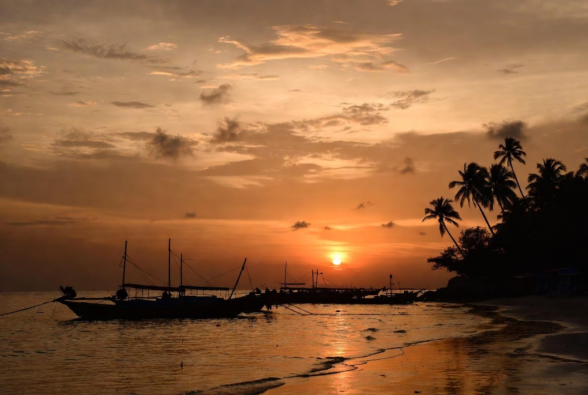 Sunset over the beach on Koh Lanta with boats silhouetted against the sky