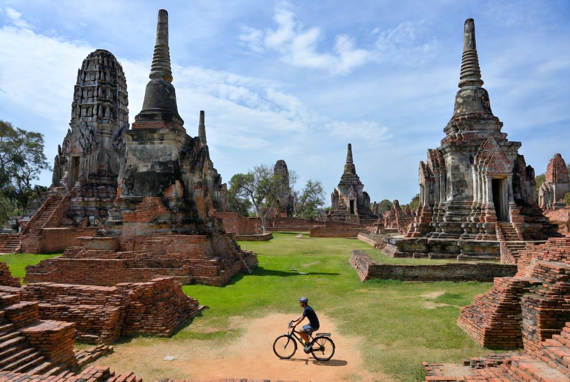 Person cycling among the ancient brick temple ruins of Ayutthaya
