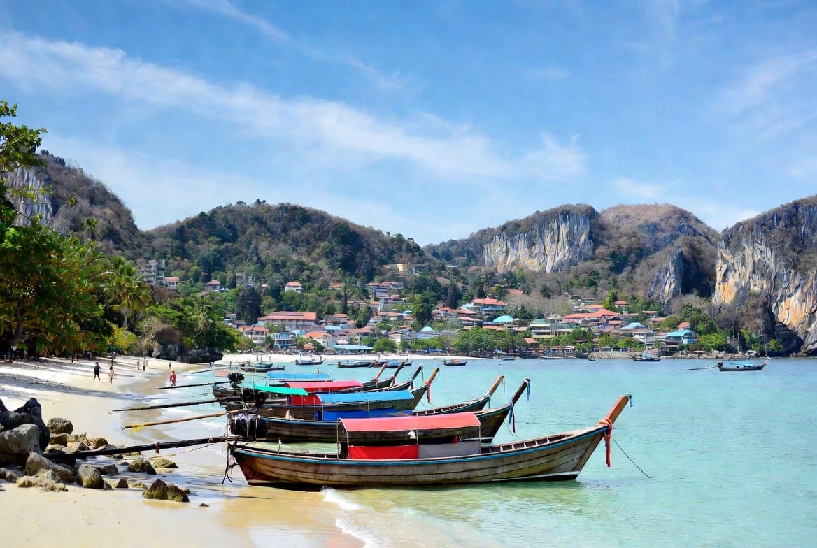 Longtail boats on the beach at Ao Nang Krabi with limestone hills behind