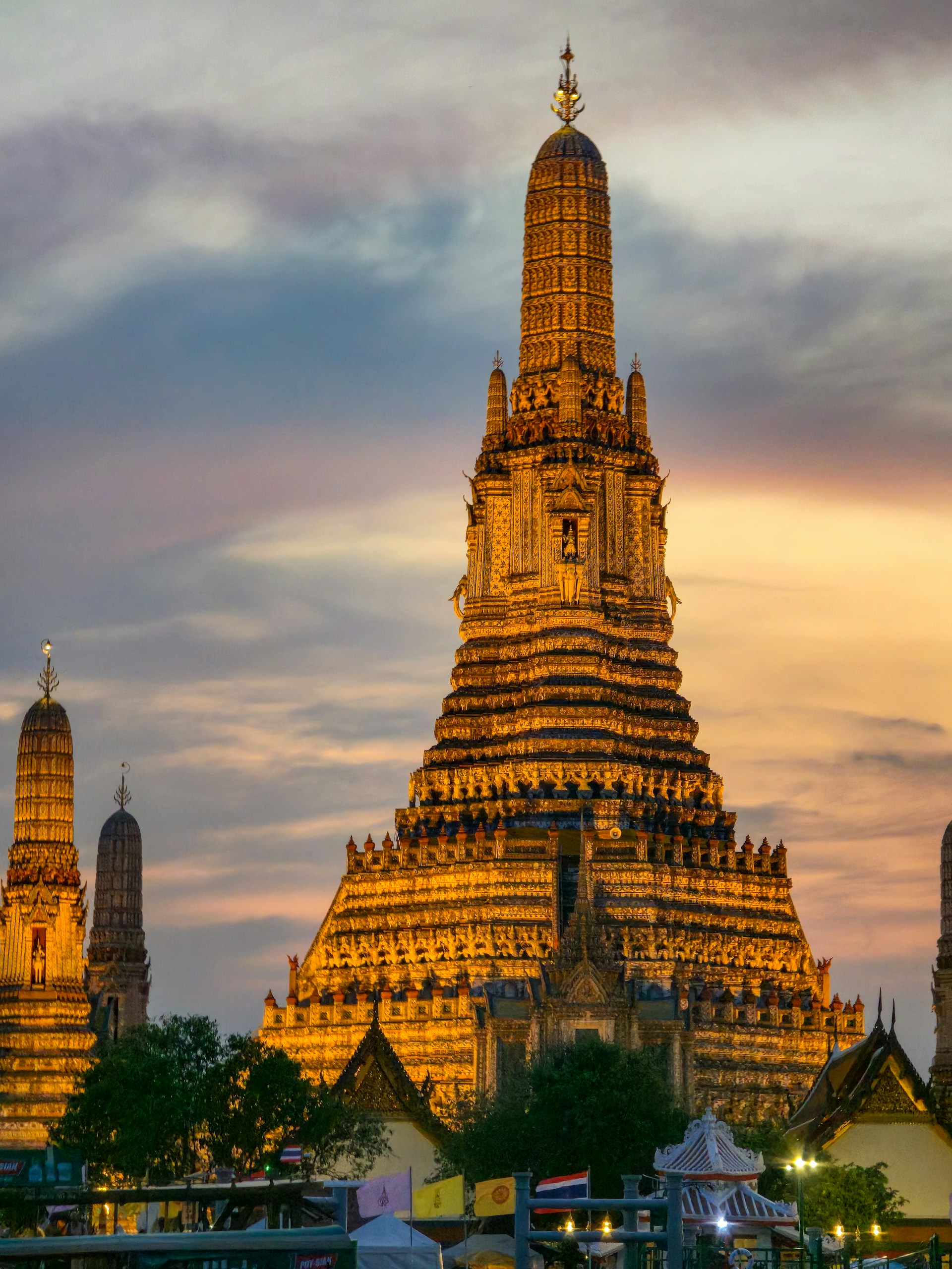 Wat Arun Temple of Dawn glowing at dusk beside the Chao Phraya River in Bangkok