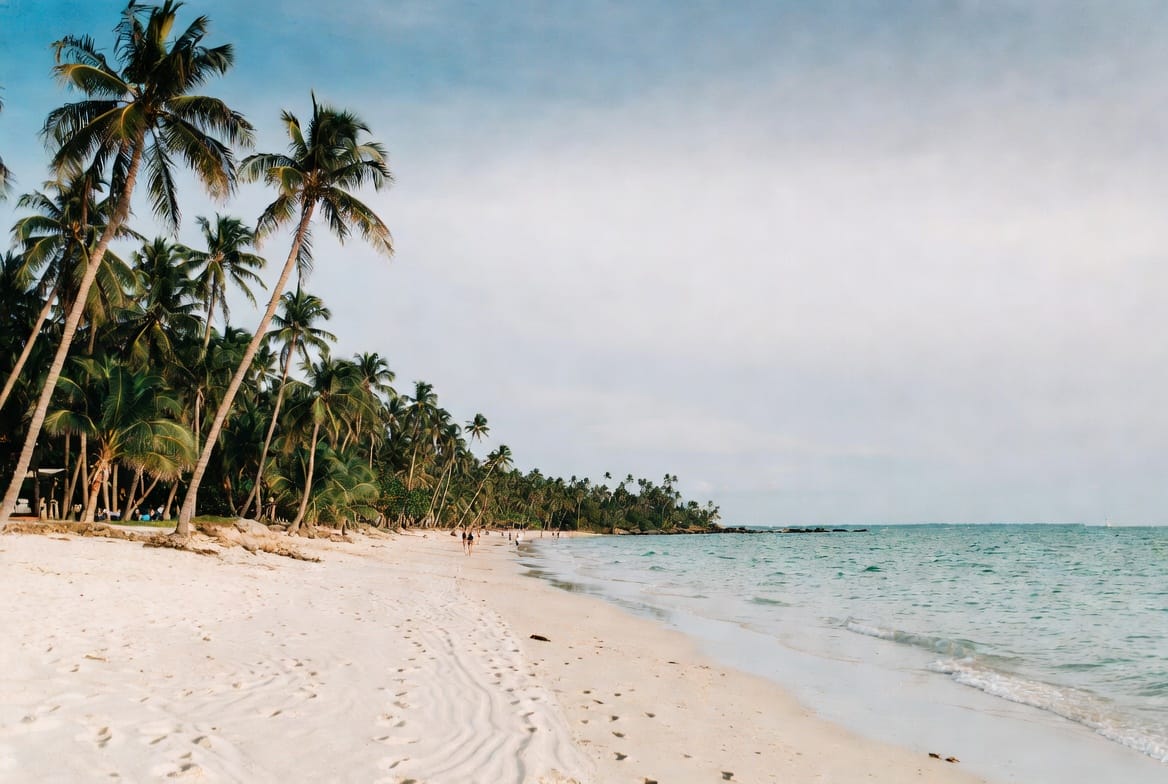 Wide sandy beach in Hua Hin with palm trees and calm turquoise water